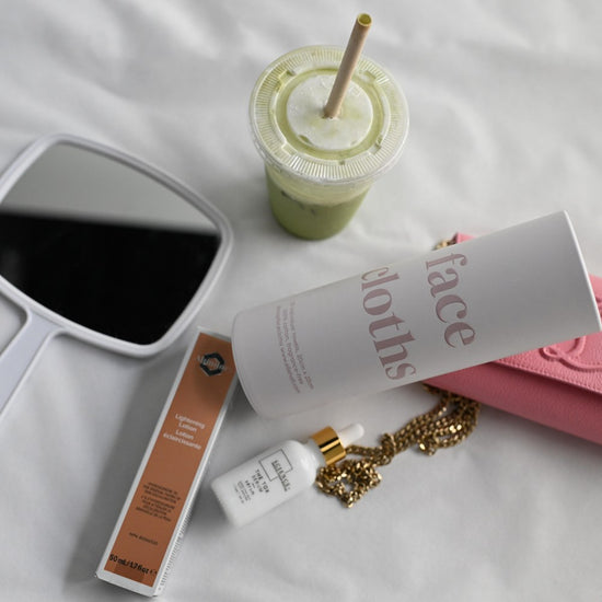 strip, face cloths on a vanity beside a matcha, a mirror and a gold chain