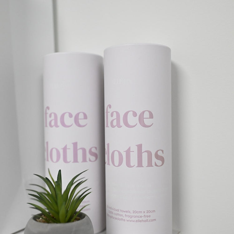 strip, two tubes of face cloths on a shelf beside a small plant