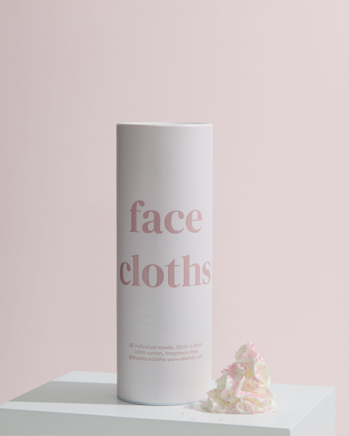 a tube of face cloths on a plinth with petals